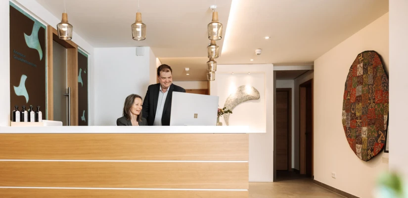 Moderne Rezeption mit freundlichem Personal in einem stilvollen Foyer, das einladend gestaltet ist.