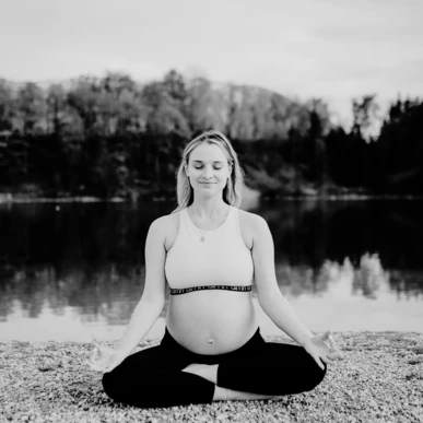 Schwangere Frau meditiert am Ufer eines Sees, umgeben von Natur, bei Ruhe und Entspannung im Wellnesshotel Klosterhof, Bayern.