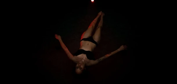 Eine Person liegt in dunklem Wasser und entspannt sich, beleuchtet von schwachem Licht.