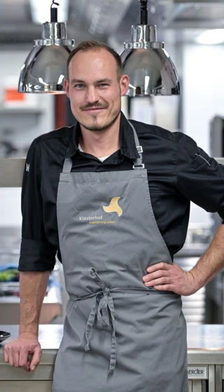 Koch in der modernen Küche des Hotel Klosterhof, umgeben von professioneller Ausstattung und einem ansprechenden Ambiente.