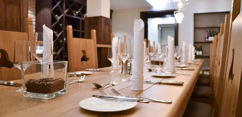 Ein eleganter Tisch im Klosterhof, liebevoll gedeckt mit Gläsern, Besteck und Servietten, umgeben von Holzdetails.