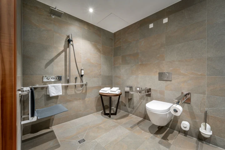 Modernes Badezimmer mit Dusche, WC und Handtuchhalter. Stilvolle Fliesen und Holzdetails schaffen eine einladende Atmosphäre.