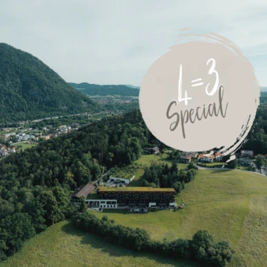 Luftaufnahme einer malerischen Landschaft mit einem Hotel und Bergen im Hintergrund, beworben mit einem speziellen Angebot.