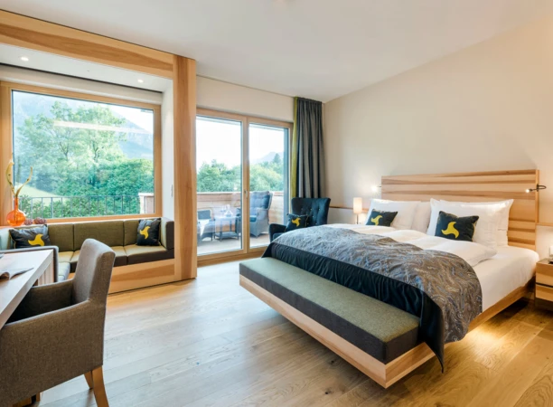 Helles, modernes Zimmer im Hotel Klosterhof mit Blick auf die Alpen, gemütlicher Sitzecke und stilvollem Dekor. Ideal für Erholung und Wellness.