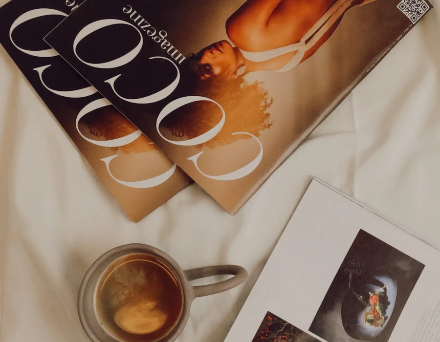 Zwei Ausgaben des Magazins "Coco" liegen auf einem weißen Tuch, daneben eine Tasse Kaffee und eine weitere Zeitschrift mit kulinarischen Bildern.