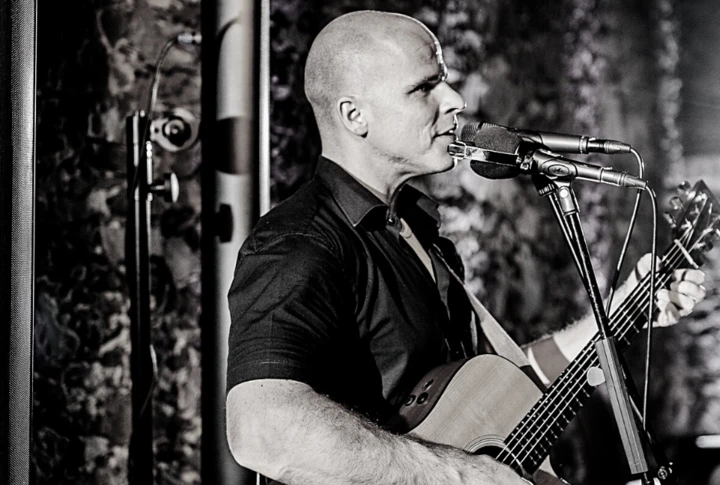 Ein Musiker mit Gitarre singt in einem stilvollen Raum des Hotels Klosterhof, umgeben von einer warmen Atmosphäre in Bayern.