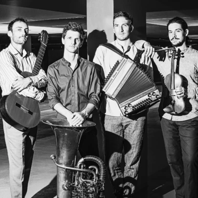 Eine Band mit Gitarre, Tuba, Akkordeon und Geige posiert in einem Parkhaus.