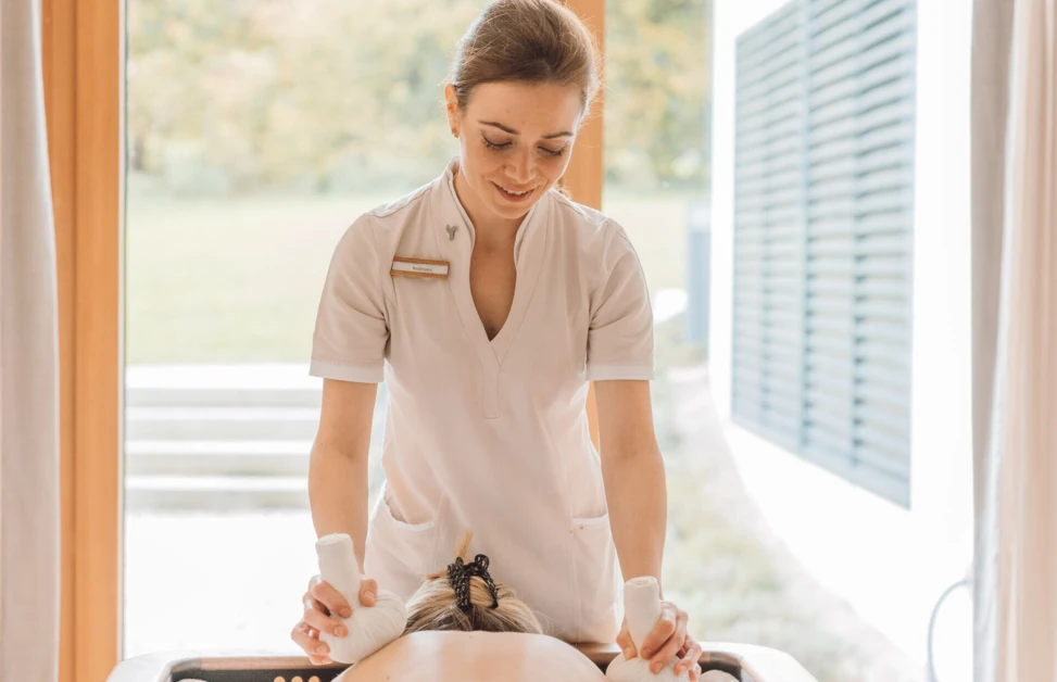 A massage therapist at Wellnesshotel Klosterhof performs a treatment in a serene setting.