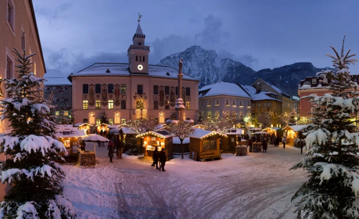 Winterliche Marktszene in Bayerisch Gmain mit festlich beleuchteten Ständen und schneebedeckten Bäumen vor dem Hotel Klosterhof.