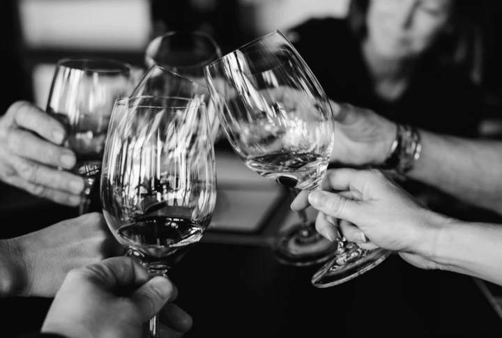 People toasting with wine glasses in a celebratory gathering.