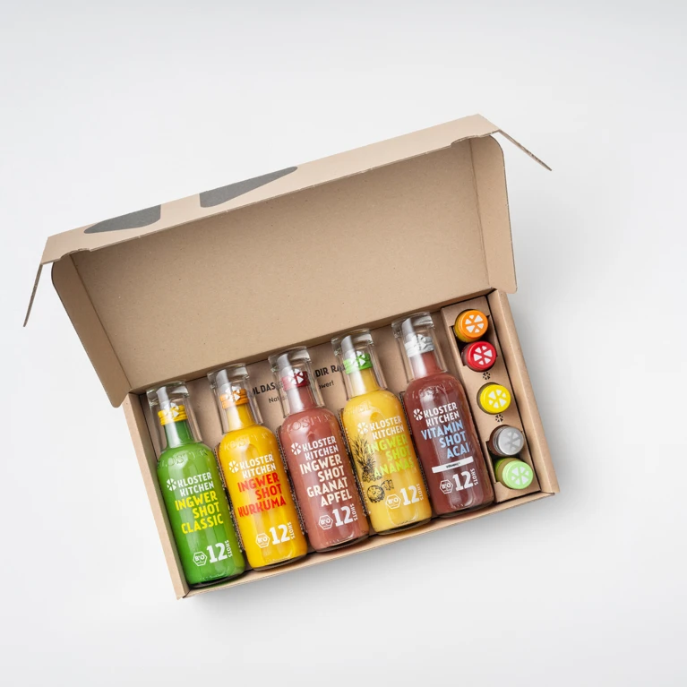 Sechs Flaschen gesunde Ingwer-Shots in einer umweltfreundlichen Verpackung, ideal für einen vitalen Lebensstil.
