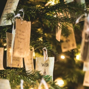 Wünsche auf Papierzetteln hängen an einem beleuchteten Weihnachtsbaum im Hotel Klosterhof.