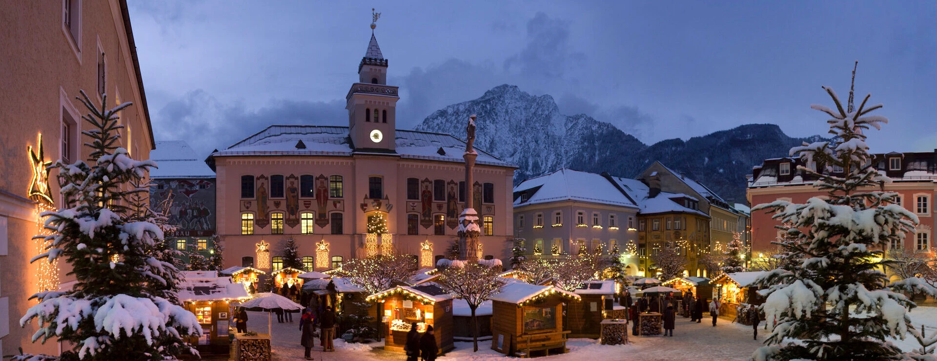 Winterliche Marktszene in Bayerisch Gmain mit festlich beleuchteten Ständen und schneebedeckten Bäumen vor dem Hotel Klosterhof.