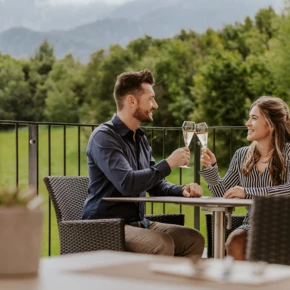 A couple toasting with champagne on a scenic outdoor terrace.