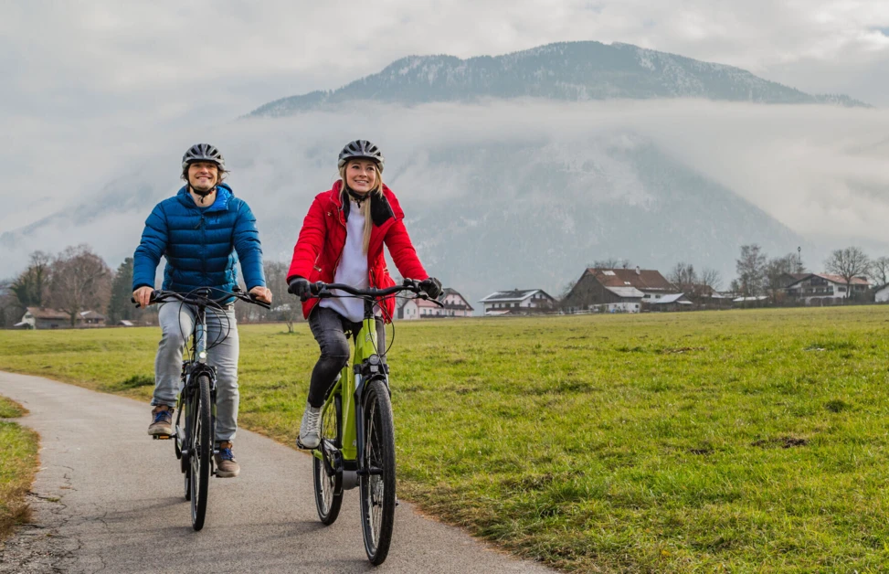 Zwei Radfahrer genießen eine entspannte Ausfahrt in der Natur, umgeben von Bergen und grünen Wiesen.