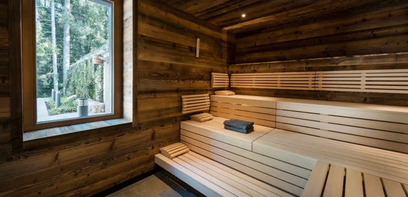 Innenansicht einer Sauna mit Holzverkleidung, Fenstern und Bänken, die eine entspannende Atmosphäre im Wellnesshotel bietet.