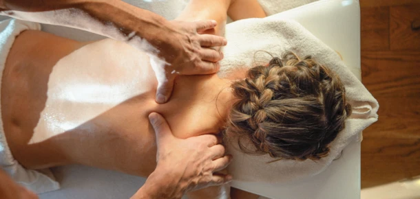 Eine Person erhält eine Rückenmassage in einem Wellnesshotel, umgeben von entspannender Atmosphäre im Hotel Klosterhof.