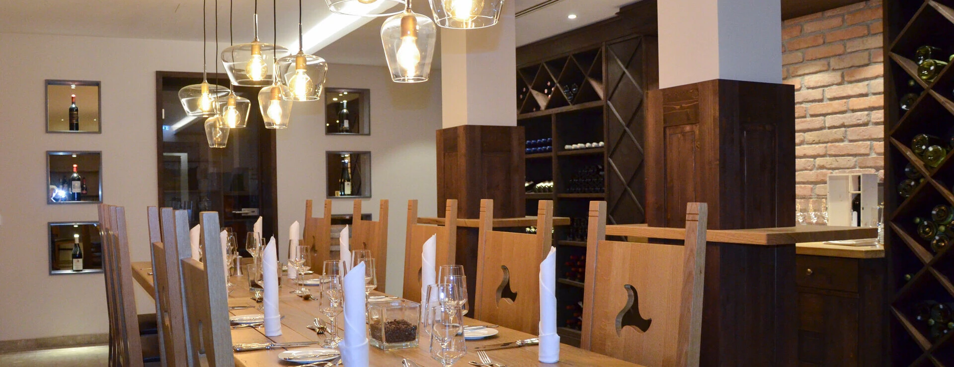 Eleganter Speisesaal im Hotel Klosterhof mit Holzdekor, stilvollen Leuchten und Weinregalen. Perfekt für gesellige Abende in Bayerisch Gmain.