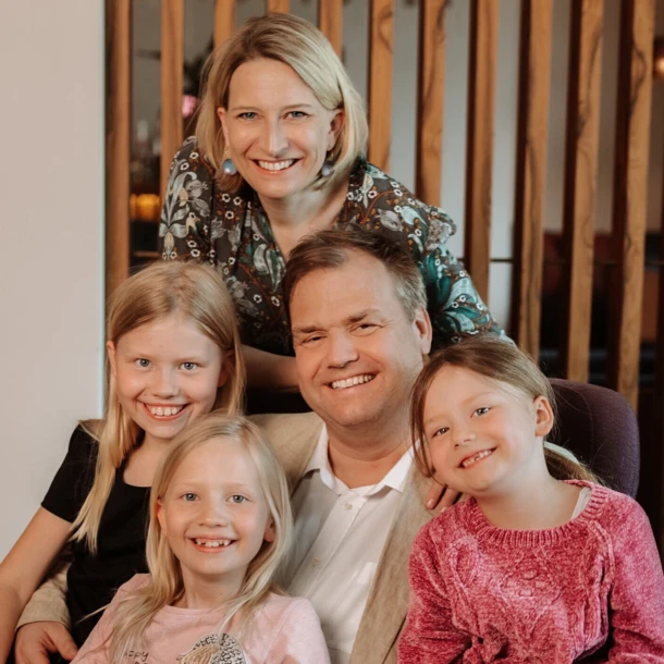 Familie posiert lächelnd zusammen, umgeben von einer warmen, einladenden Atmosphäre.