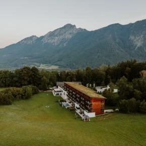 Aerial view of Hotel Klosterhof surrounded by lush greenery and mountains in the background.