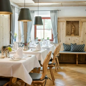 Helles, einladendes Restaurant mit Holzelementen, eleganten Tischgedecken und gemütlicher Atmosphäre.
