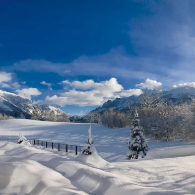 Schneebedeckte Landschaft mit Blick auf die Berge und das Hotel Klosterhof in Bayerisch Gmain. Helle, sonnige Atmosph&auml;re.