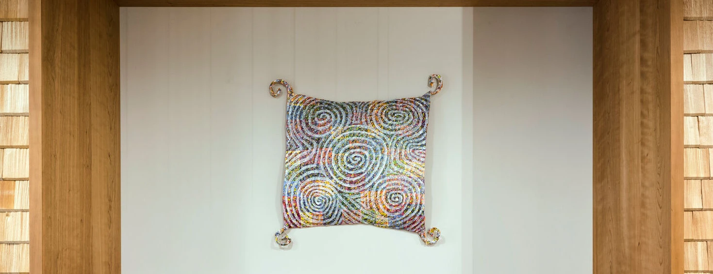 Ein gemütlicher Sitzbereich mit roten Sofas und buntem Wandkunstwerk, umgeben von Holzverkleidung.