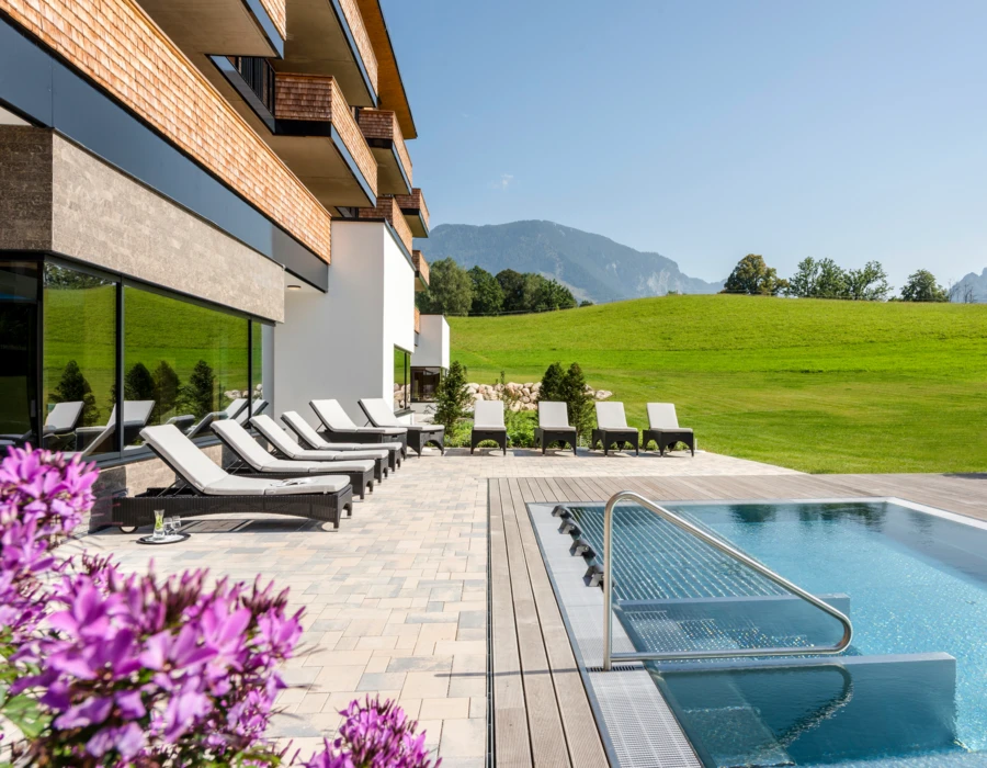Außenbereich des Wellnesshotels Klosterhof in Bayerisch Gmain mit Pool, Liegestühlen und Alpenblick. Perfekt für Entspannung in Bayern.