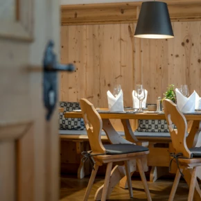 Gemütlicher Essbereich mit Holztisch, gedeckt mit Gläsern und Servietten, in einem stilvollen, holzgetäfelten Raum.
