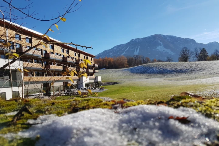 Moderne Unterkunft mit Bergblick, umgeben von Schnee und gr&uuml;nem Rasen, ideal f&uuml;r Erholung und Naturerlebnisse.