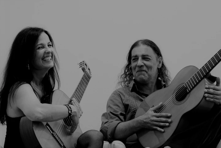 Zwei Musiker lächeln und spielen Gitarre in entspannter Atmosphäre im Hotel Klosterhof, einem Wellnesshotel in Bayern.