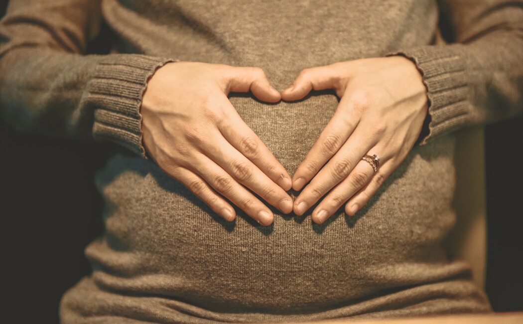 Frau mit Hände auf Babybauch beim Babymoon in Bayern.