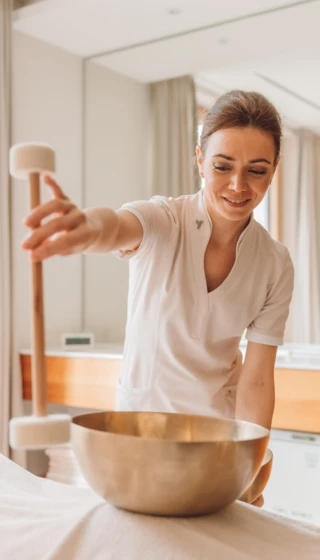 Eine Fachkraft bereitet eine Klangschale f&uuml;r eine Wellnessbehandlung im Hotel Klosterhof vor. Entspanntes Ambiente in Bayern.