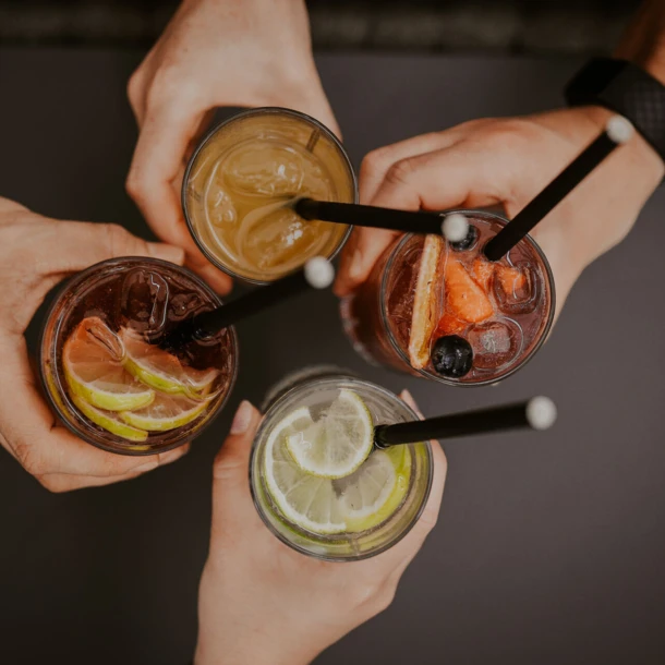 Verschiedene Cocktails werden von mehreren Händen gehalten, ideal für gesellige Momente im Hotel Klosterhof.
