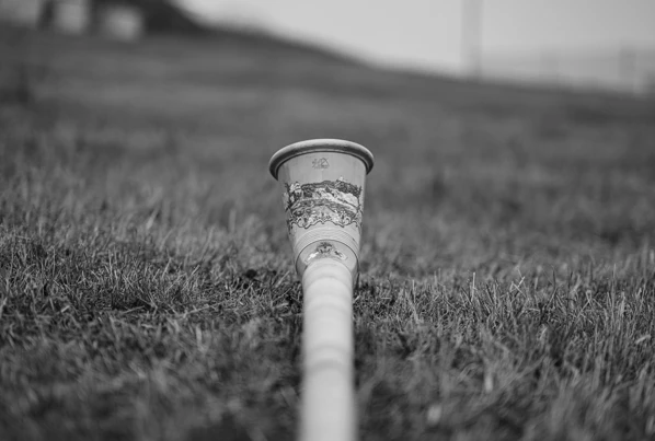Ein Blick auf einen dekorativen Becher, der im Gras liegt, vor einer sanften, verschwommenen Landschaft. Ideal für entspannende Momente im Hotel Klosterhof.