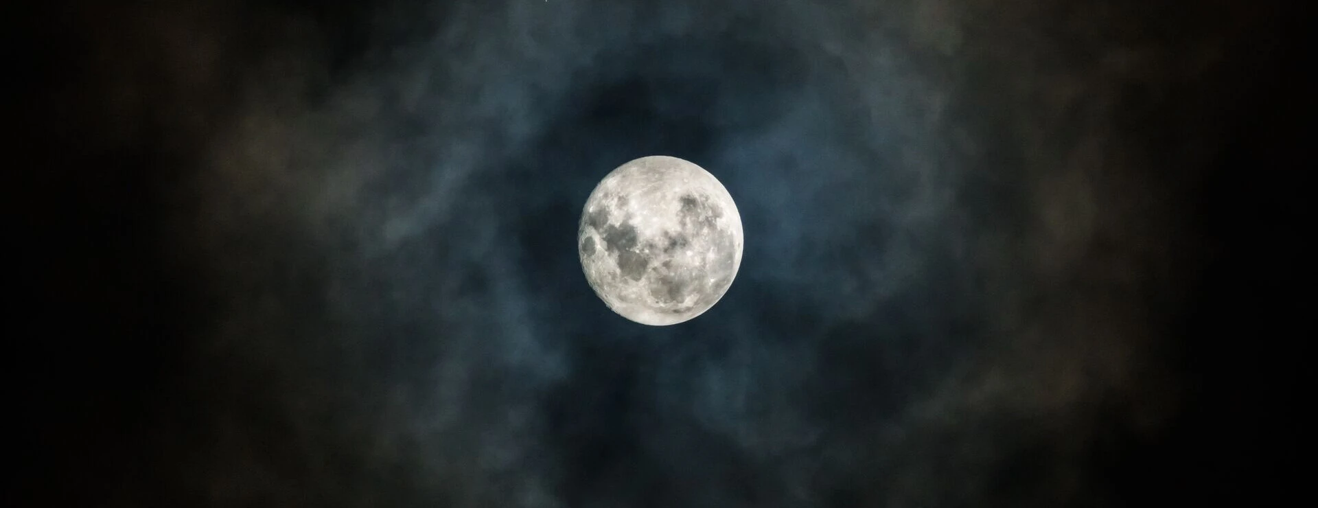 Der Mond leuchtet hell durch einen mystischen Wolkenring über Bayerisch Gmain.
